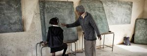 Teacher and school kid in front of black board